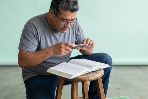 Man in his late forties scanning a textbook page with his phone.